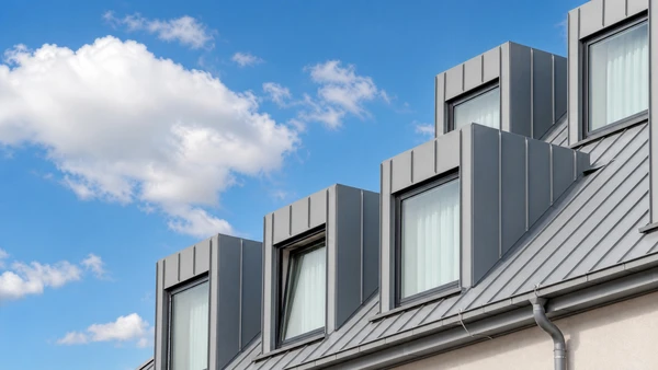 Extérieur d'une habitation, personne effectuant l'entretien de gouttière en PVC noir