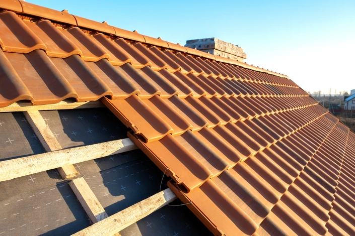 Chantier extérieur de toiture avec ouvrier appliquant un revêtement d'étanchéité au chalumeau sur membrane bitumineuse